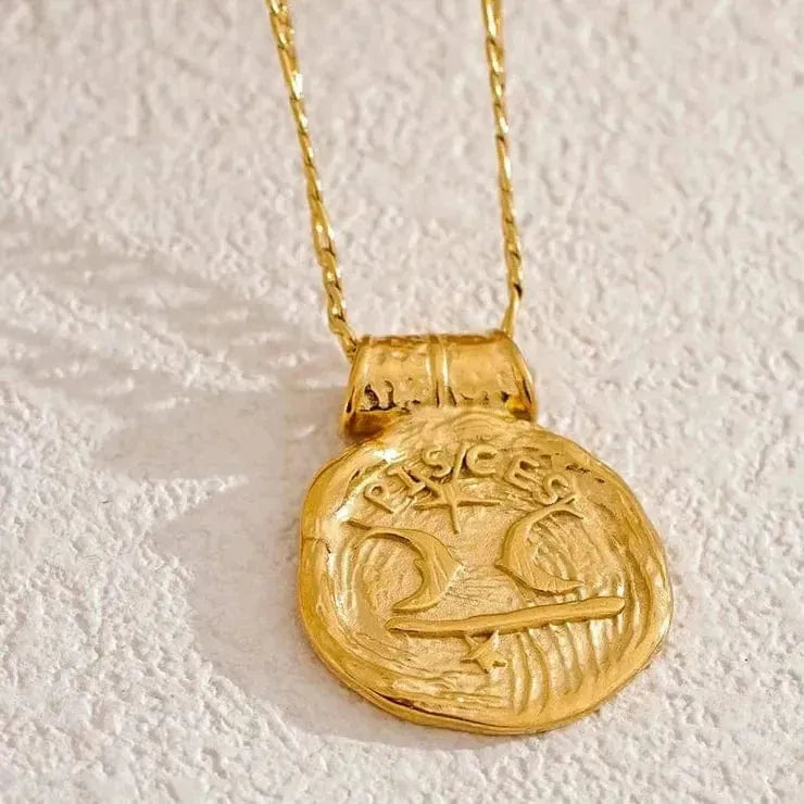 Gold necklace with a detailed pendant on a textured beige background