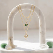 Jewelry display with necklaces on a marble stand, featuring text about product quality and brand ethos.