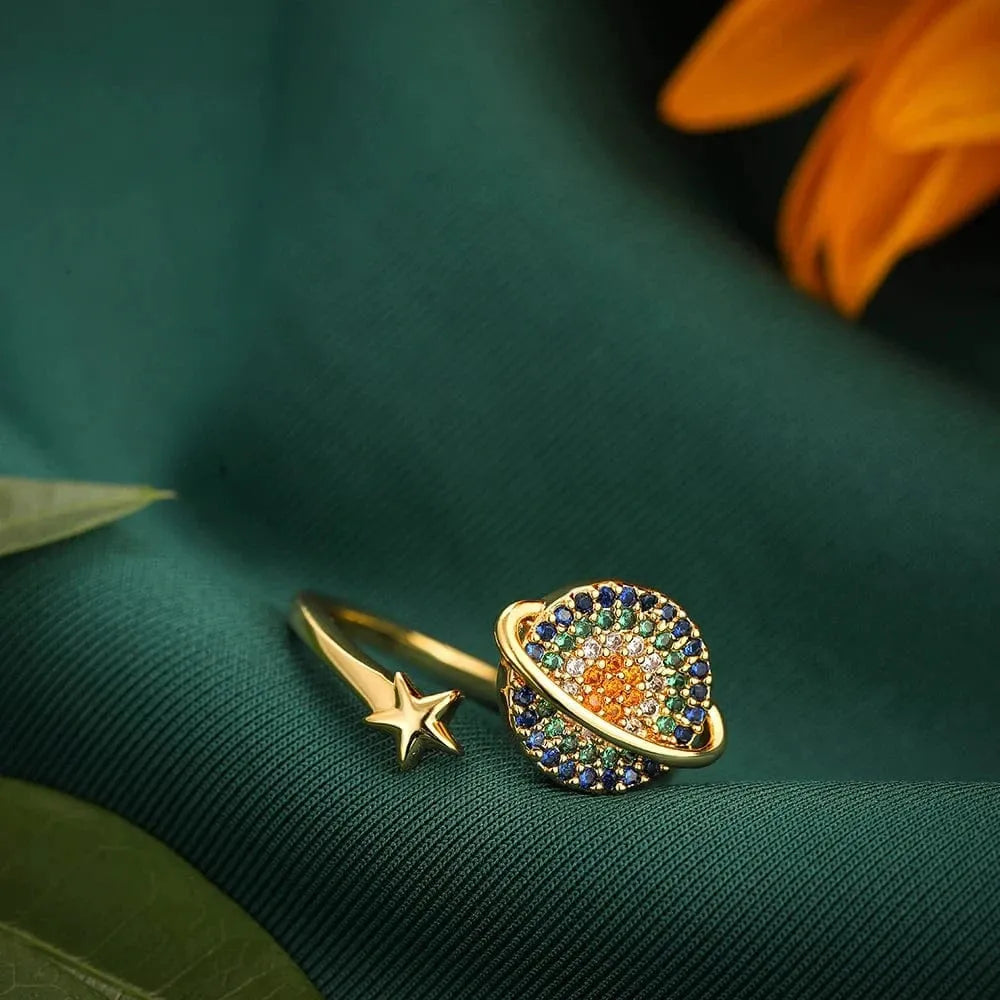 Gold ring with colorful gemstones on a green fabric background