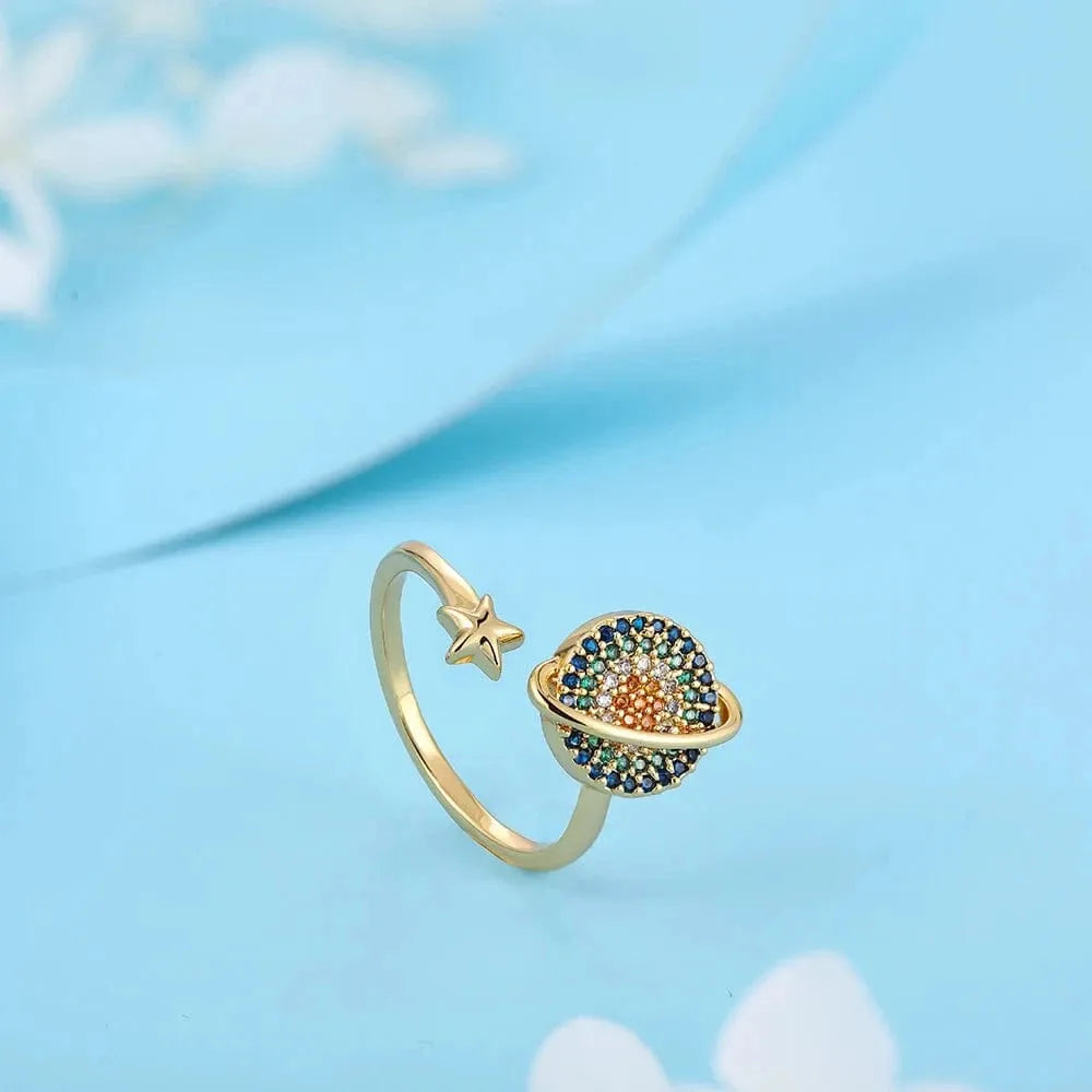 Gold ring with star and colorful gemstone design on a light blue background