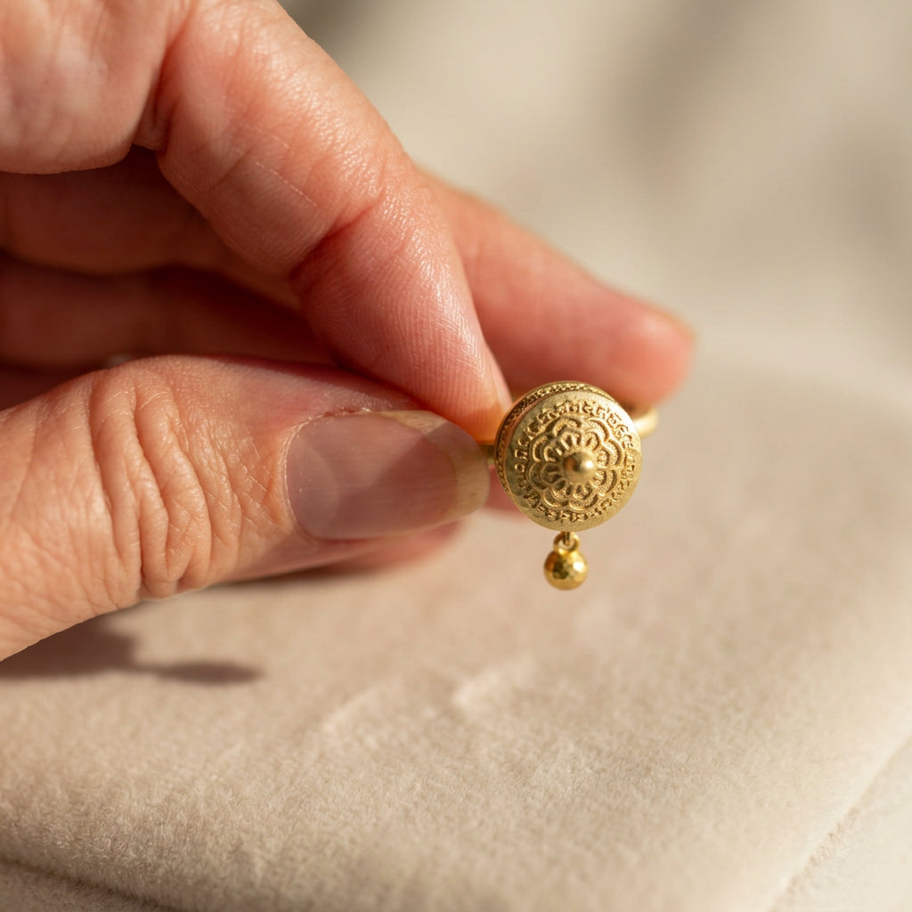 Gold-plated prayer wheel spinner ring held in the palm to show its size