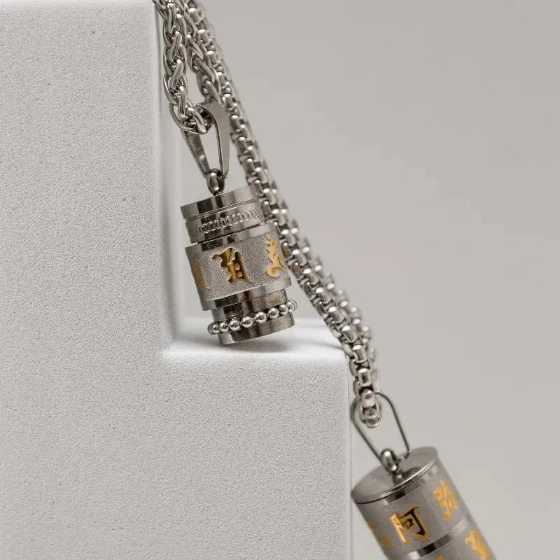Silver necklace with two cylindrical pendants on a light gray background