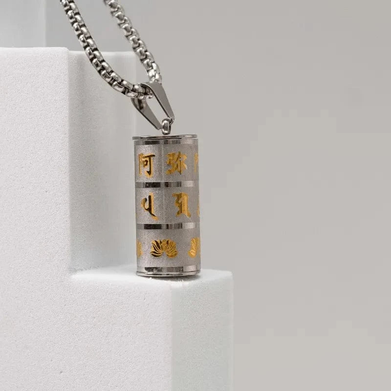 Silver cylindrical pendant with gold text on a white pedestal