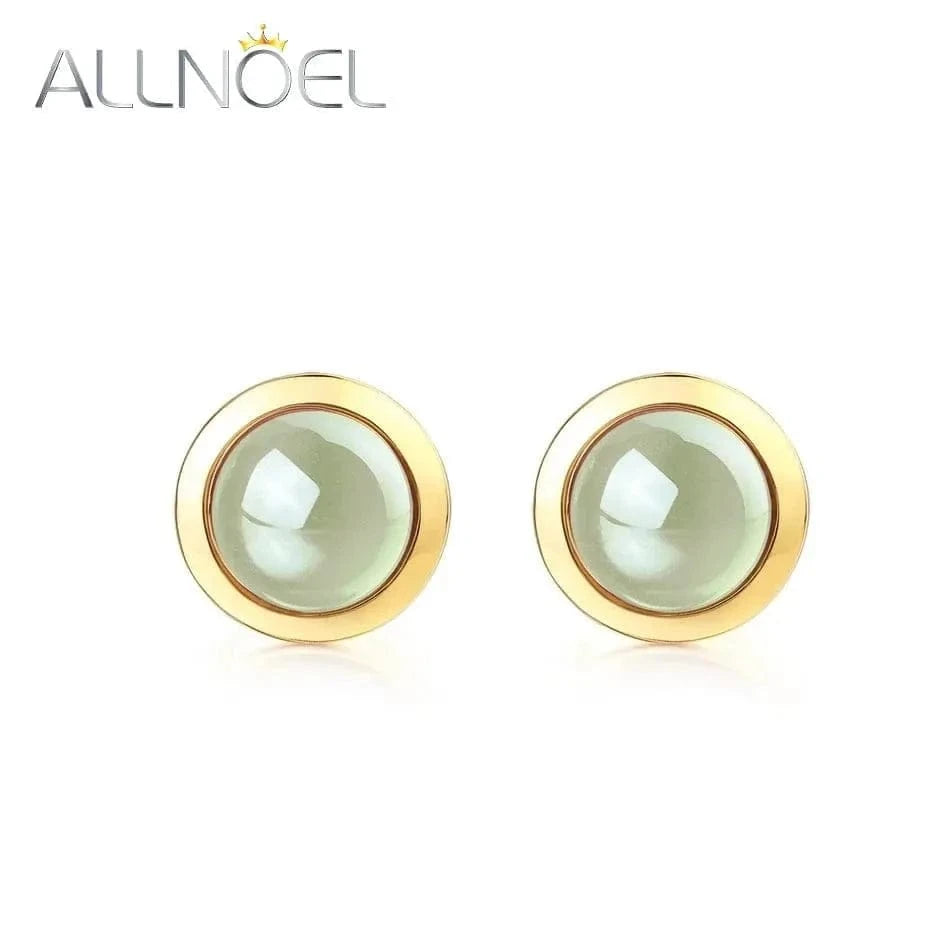 Gold earrings with a light green gemstone on a white background