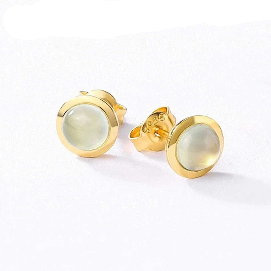 Gold earrings with a light stone on a white background