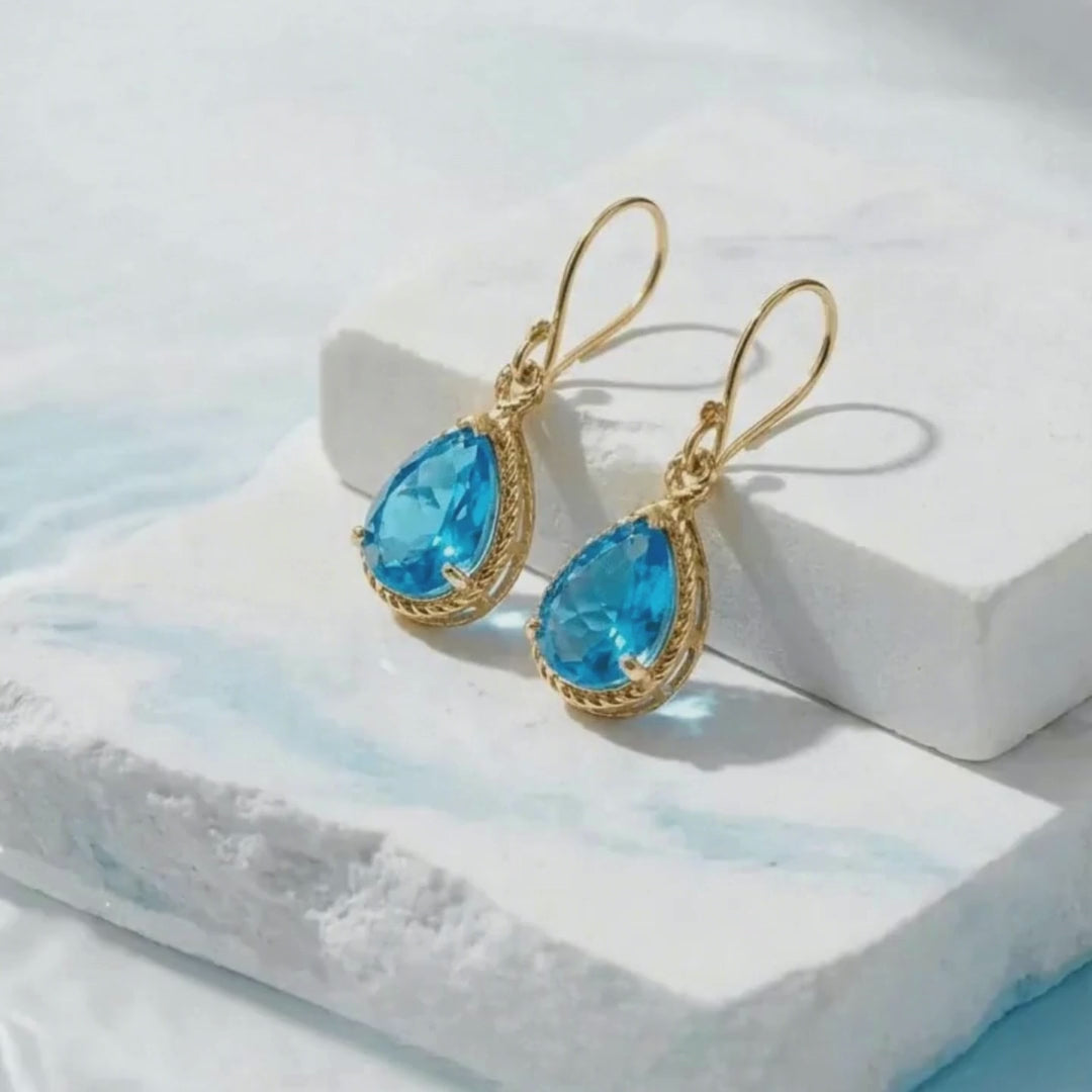 Load video: white stone background with water and vivid blue gold earrings