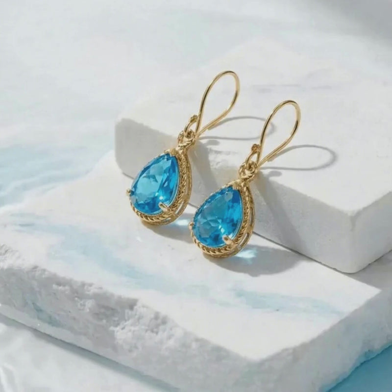 white stone background with water and vivid blue gold earrings