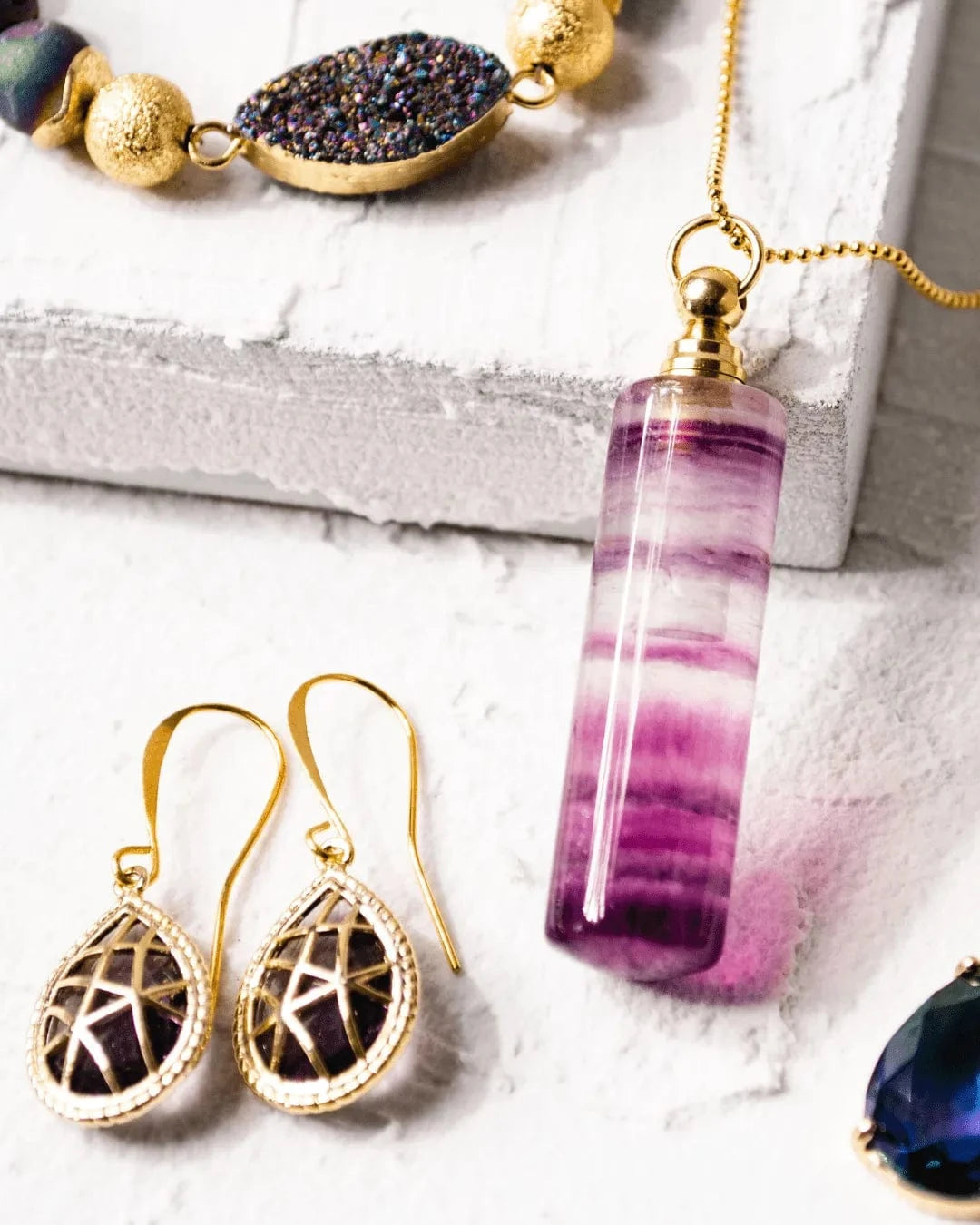 Jewelry set with purple pendant and gold earrings on a light background