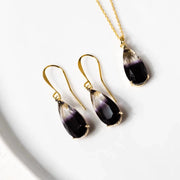 Teardrop-shaped purple and gold jewelry set on a white background