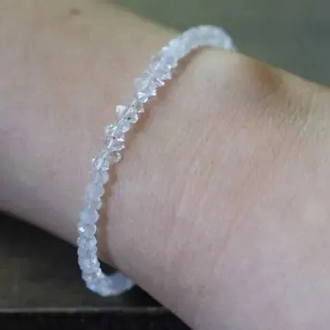 Close-up of a wrist wearing a delicate bracelet on a neutral background