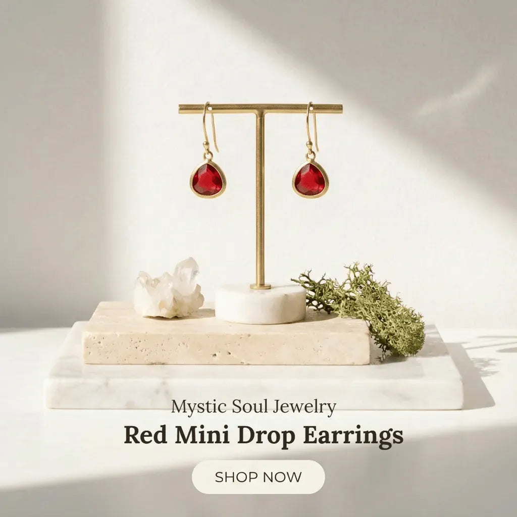 Red drop earrings on a gold earring stand with decorative elements on a light background