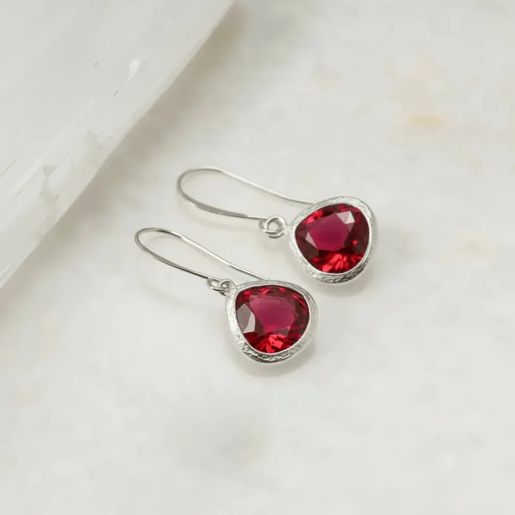 Silver earrings with red gemstones on a white surface