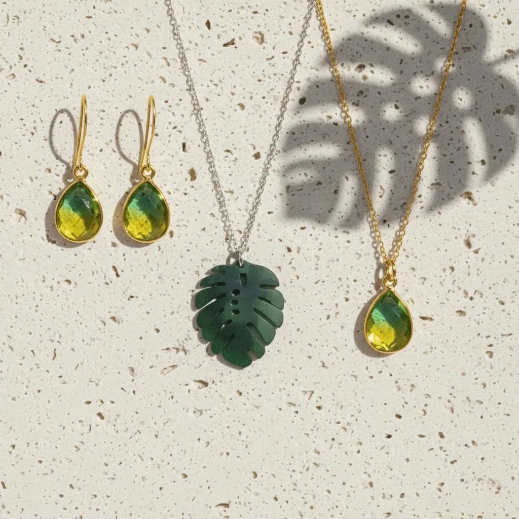 Jewelry set with green teardrop pendants on a textured surface