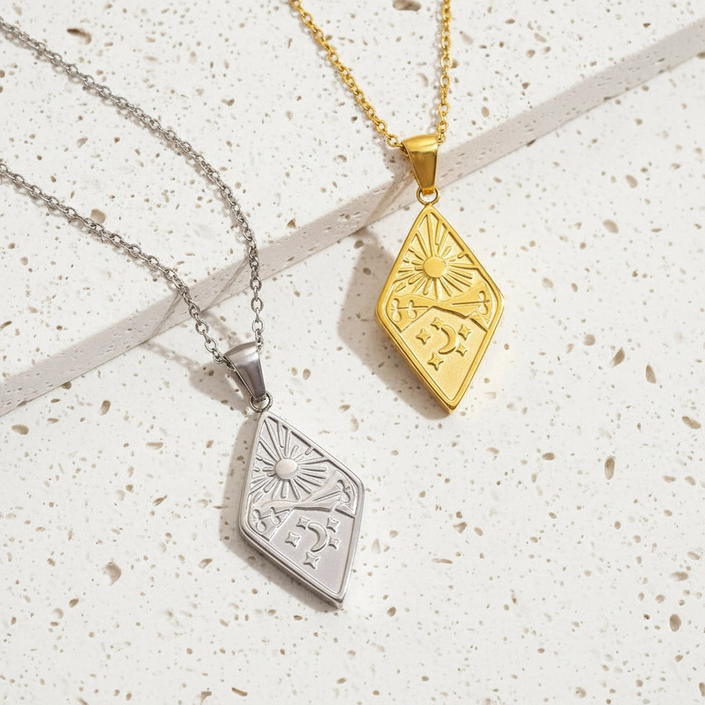 Two diamond-shaped pendants, one gold and one silver, on white  