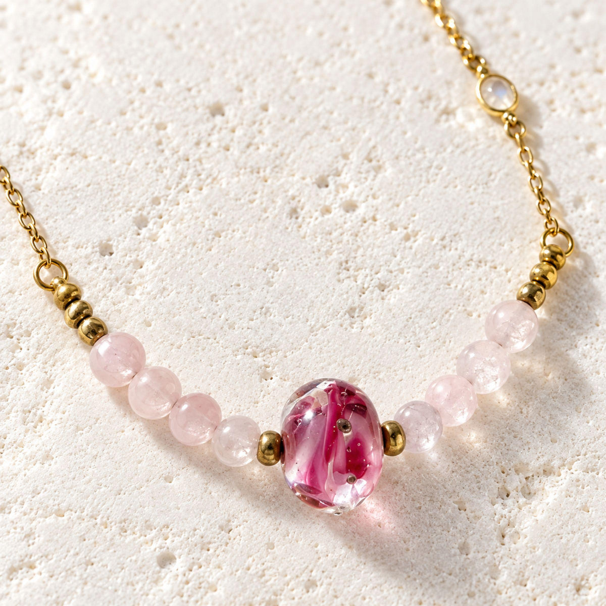 Close-up of the pink handblown glass focal bead framed by pale pink rose quartz rounds and fair trade Ghana brass beads