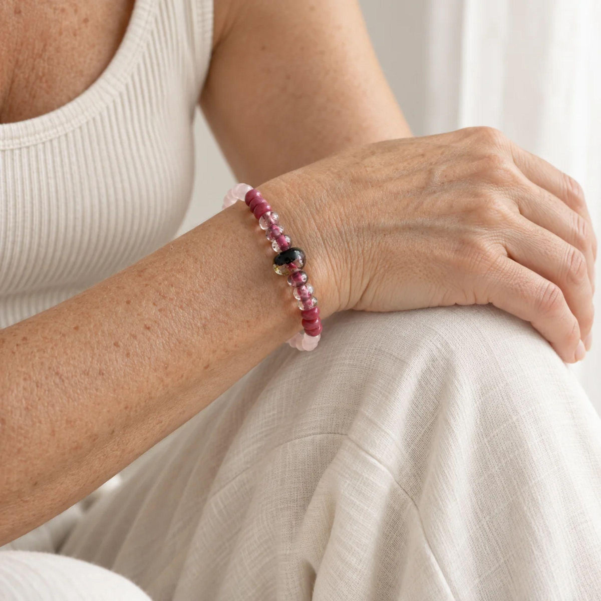 One-of-a-kind rose quartz and handblown glass stretch bracelet in soft pinks with a single dark gold-flecked focal bead