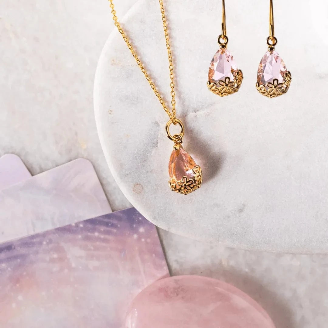 Jewelry set with pink teardrop pendant necklace and earrings on a marble surface