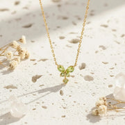 Gold necklace with green gemstones on a decorative white background