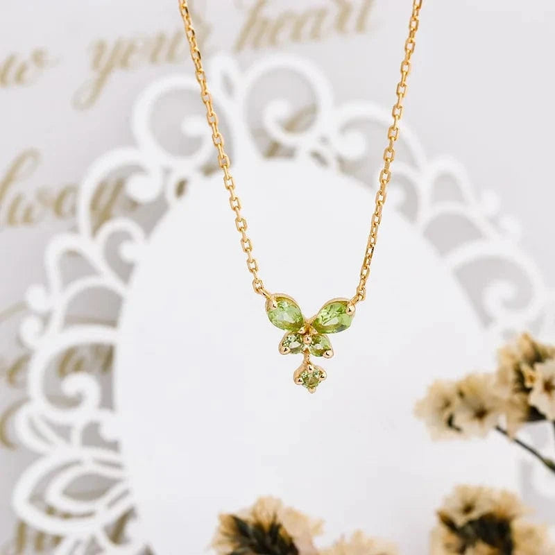 Gold necklace with green gemstones on a decorative white background