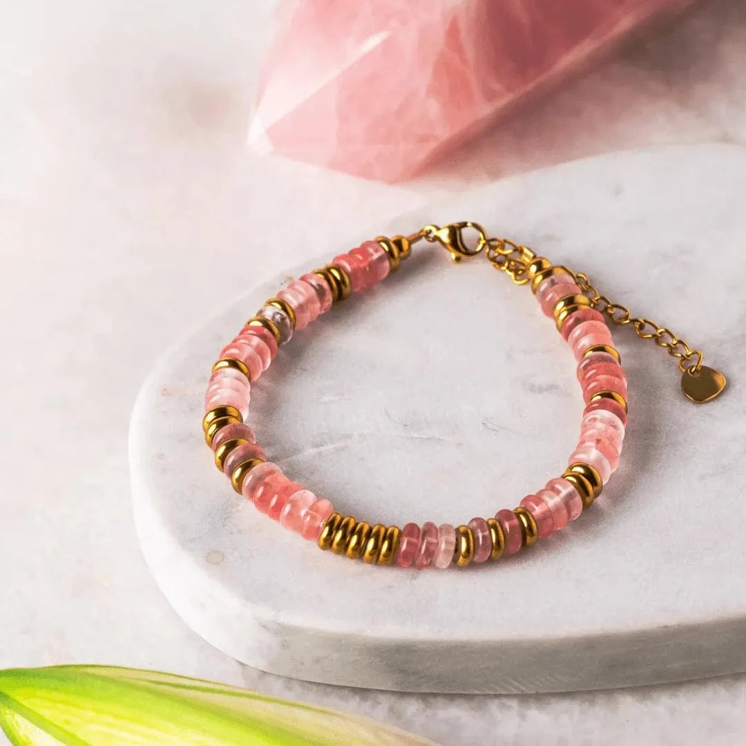 Bracelet with pink beads and gold accents on a marble surface