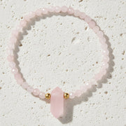 Pink beaded bracelet with a heart-shaped pink stone on a white background