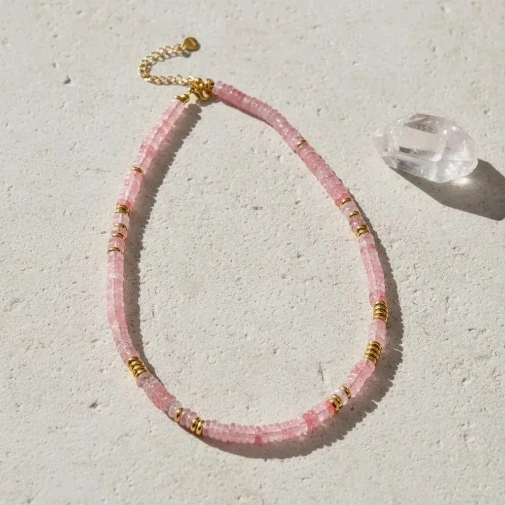 Necklace with pink beads and gold accents on a white background