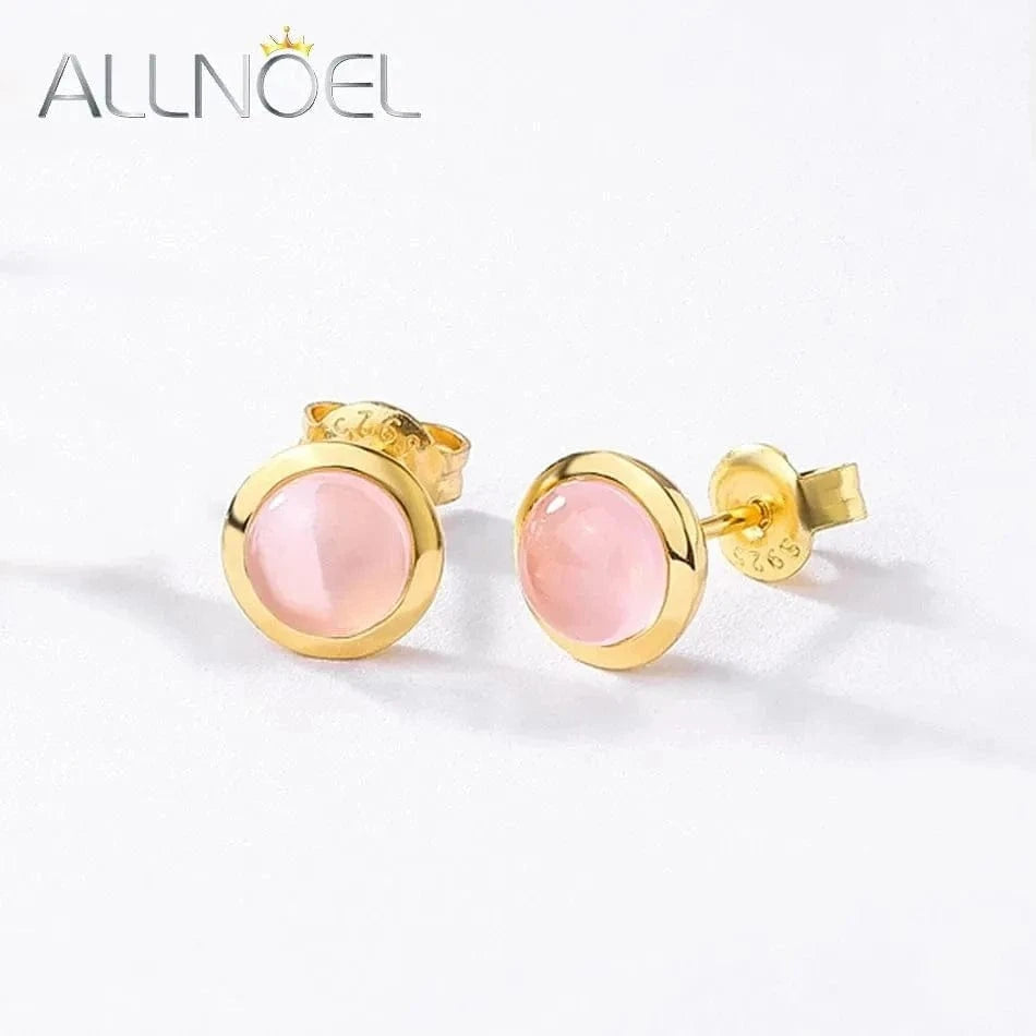 Gold earrings with pink gemstones on a white background