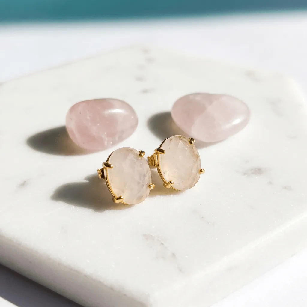 Pair of gold-framed rose quartz earrings on a marble surface