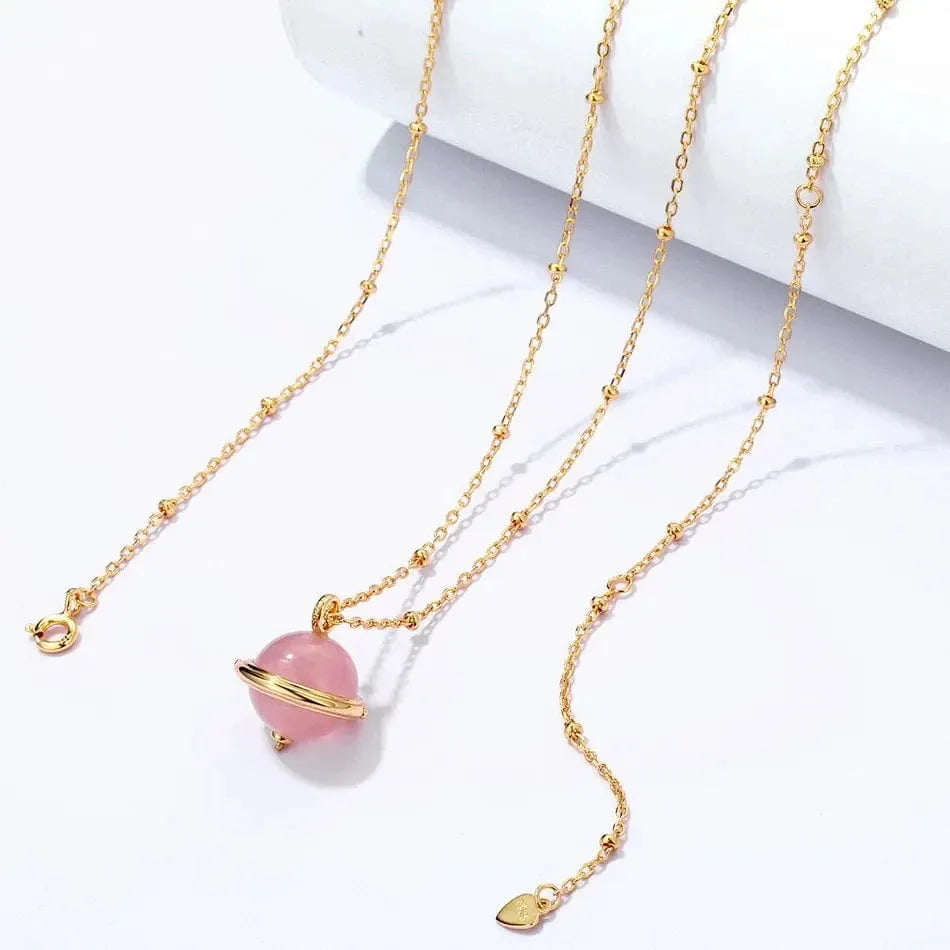 Gold necklace with a pink bead pendant on a white background