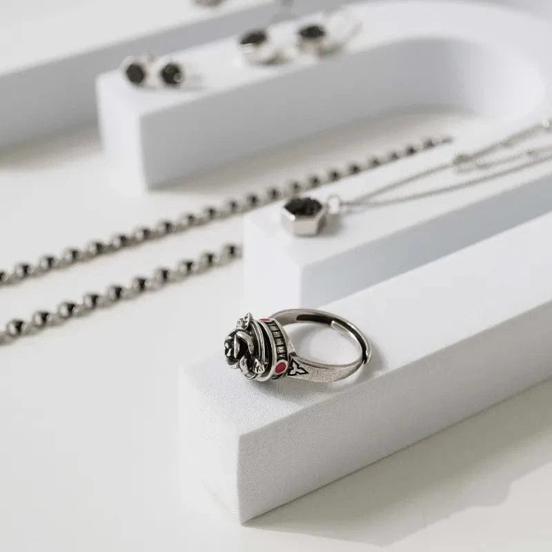 Silver ring with black gemstone and red accents on a white surface