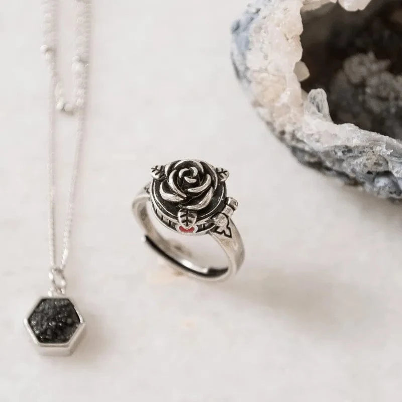 Silver ring with rose design and necklace on a light background