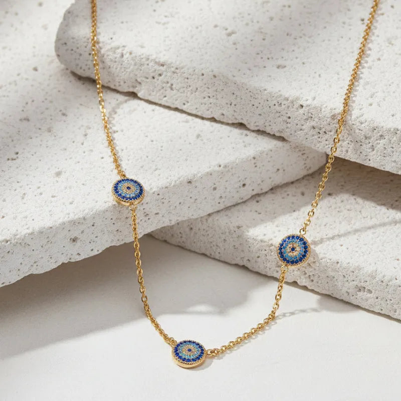 Gold necklace with three circular pendant beads on a white background