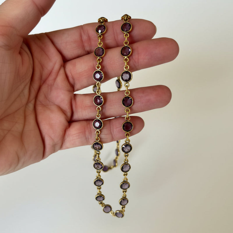 Amethyst purple faceted hydro quartz bead necklace on gold plated chain held in hand
