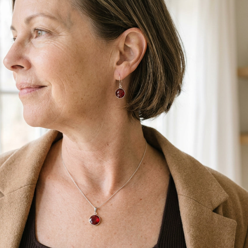 Woman wearing a silver round ruby red hydro quartz necklace and matching drop earrings set
