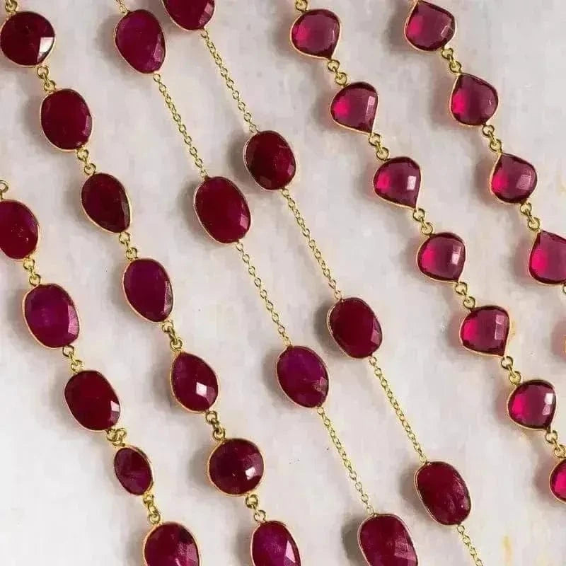 Necklace with red gemstones and gold chain on a light background