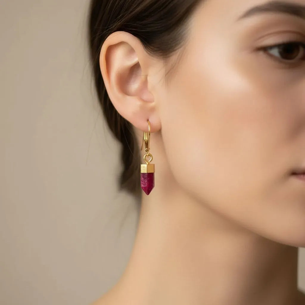 Gold earrings with red gemstones on a white background
