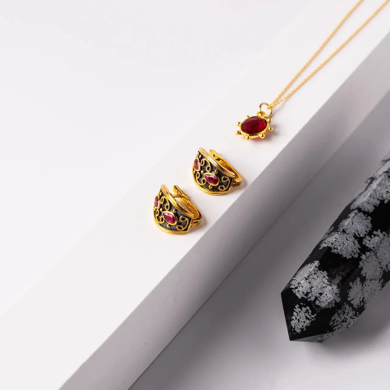 Gold jewelry with red gemstones on a white surface