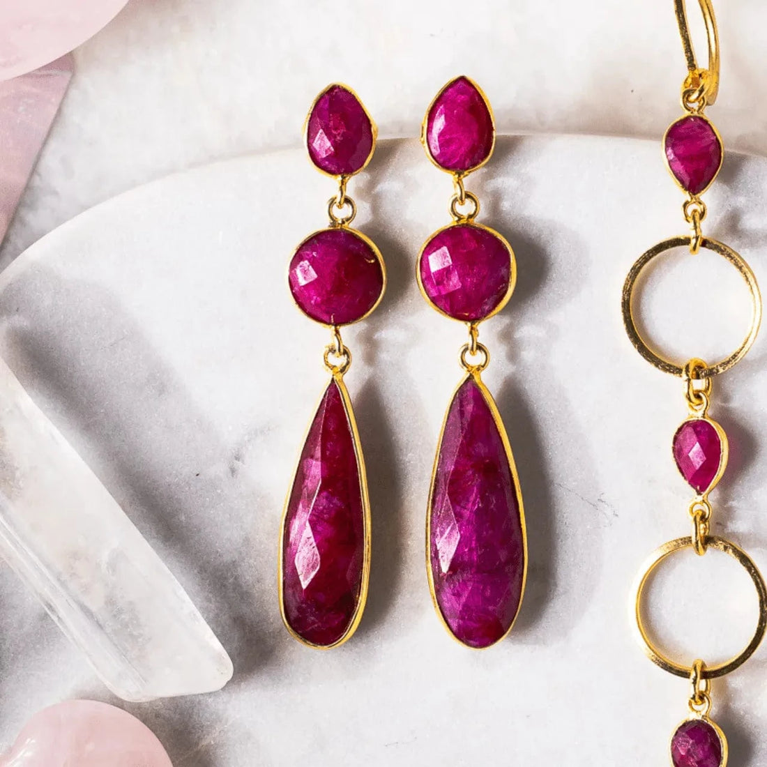 Pair of pink gemstone earrings with gold accents on a marble surface