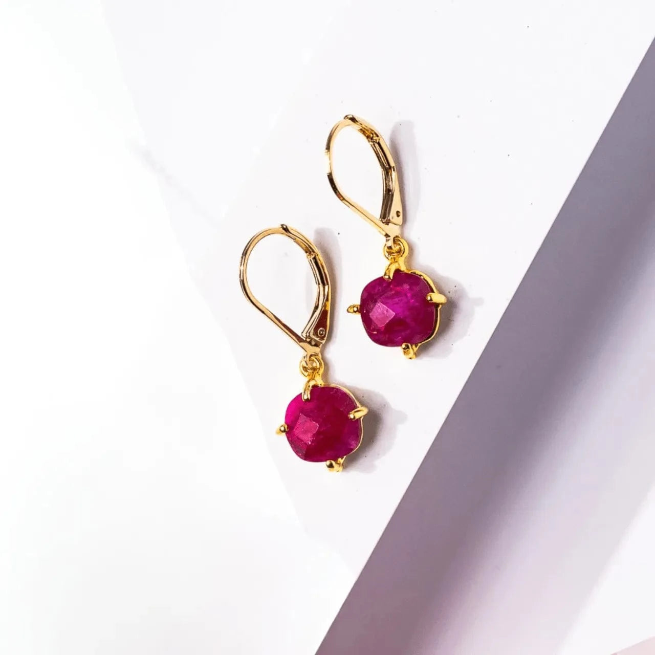 Gold earrings with red gemstones on a white background