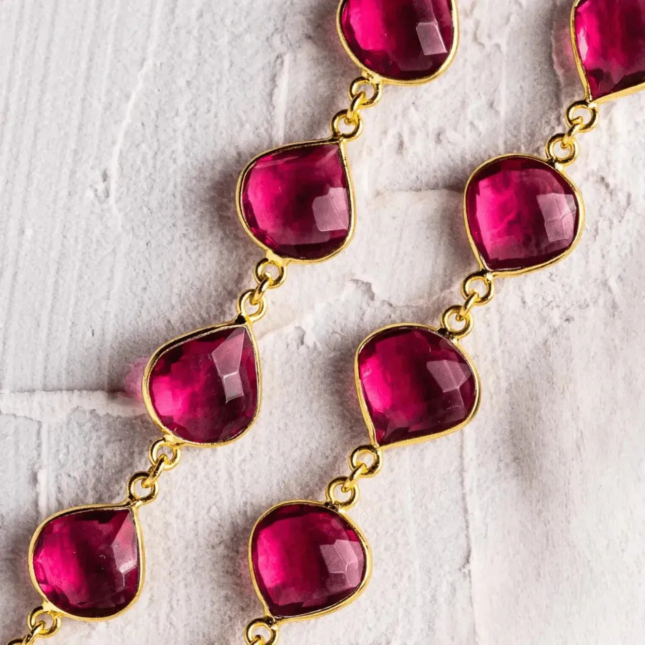 Necklace with pink teardrop-shaped gemstones on a textured white surface