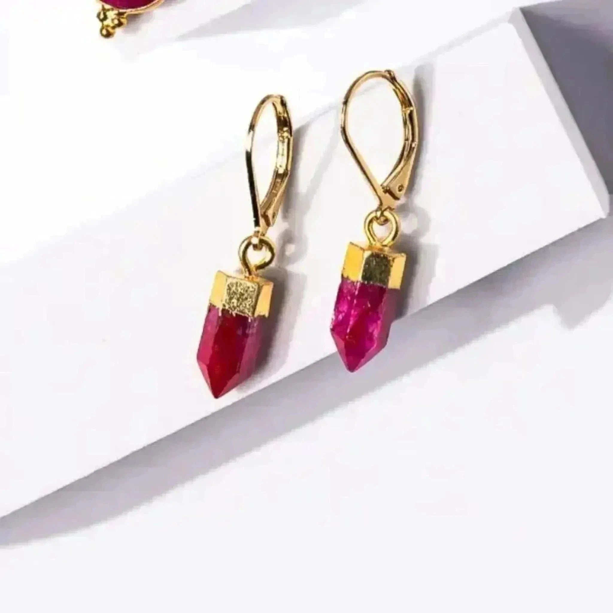 Gold earrings with red gemstones on a white background