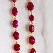 Gold necklace with red gemstones on a white marble surface