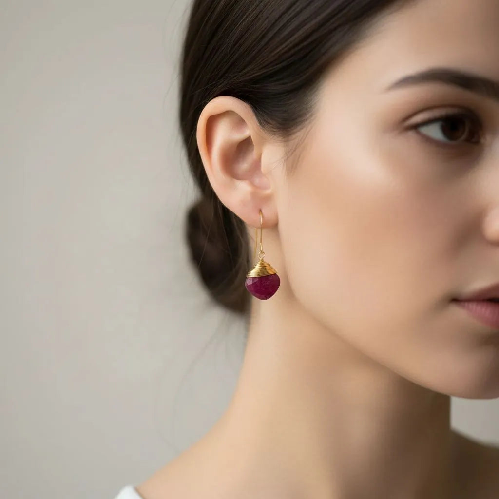 Gold earrings with pink gemstones on a white background