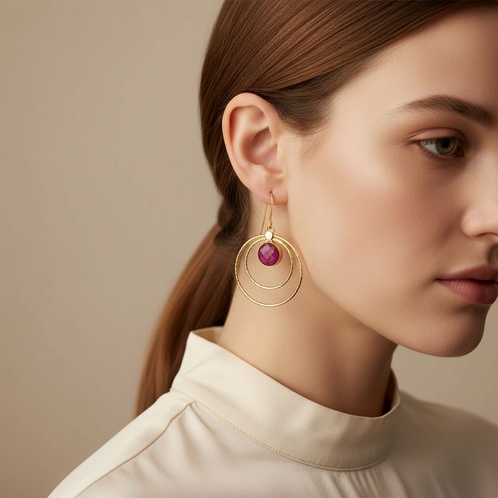 Gold earrings with pink gemstones on a white surface