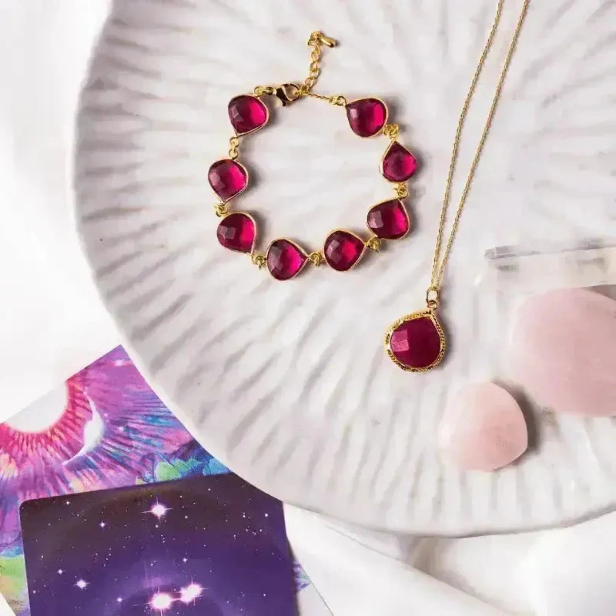 flay lay plate with ruby necklace and bracelet, vibrant tarot cards and cyrstals