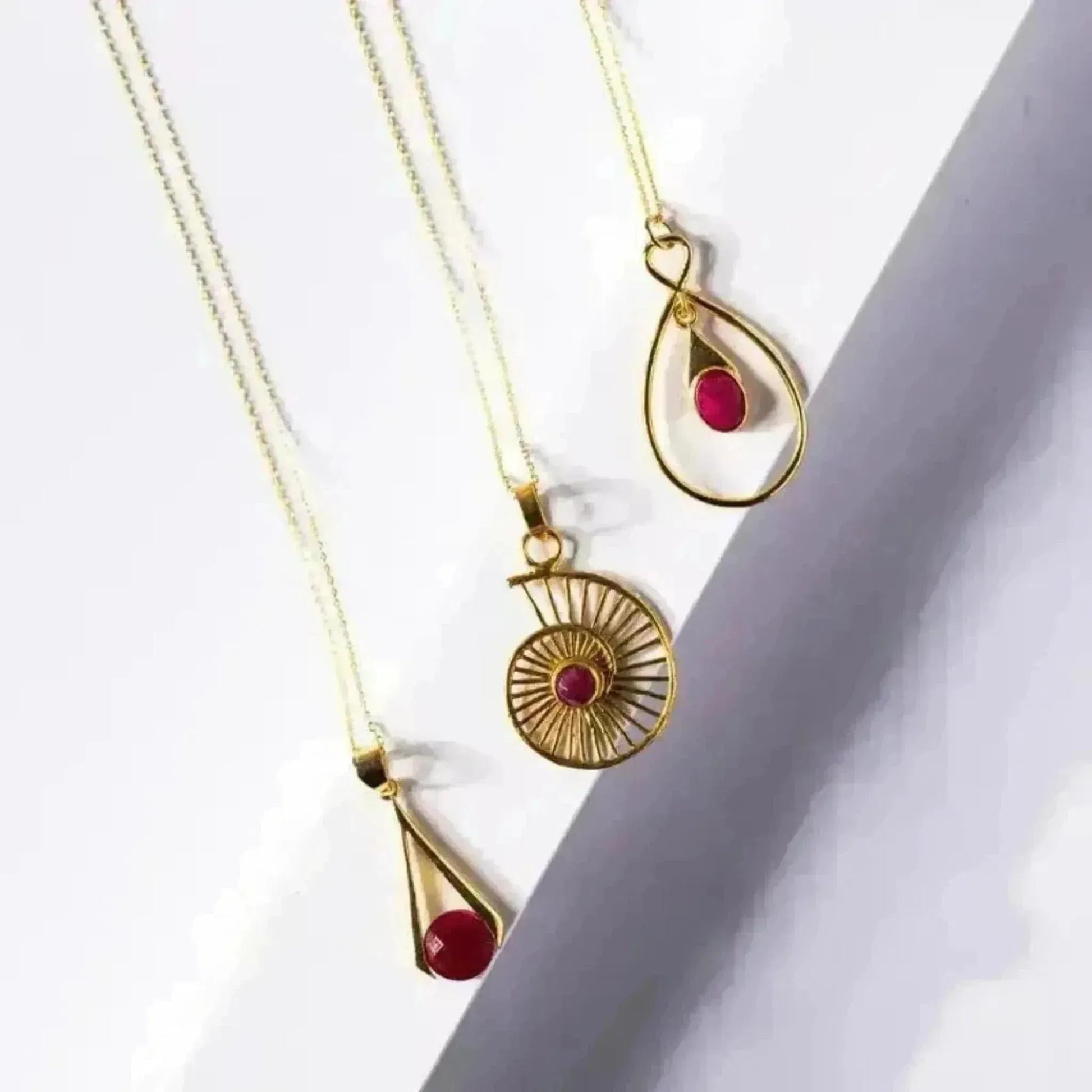 Gold necklaces with red gemstones on a white background