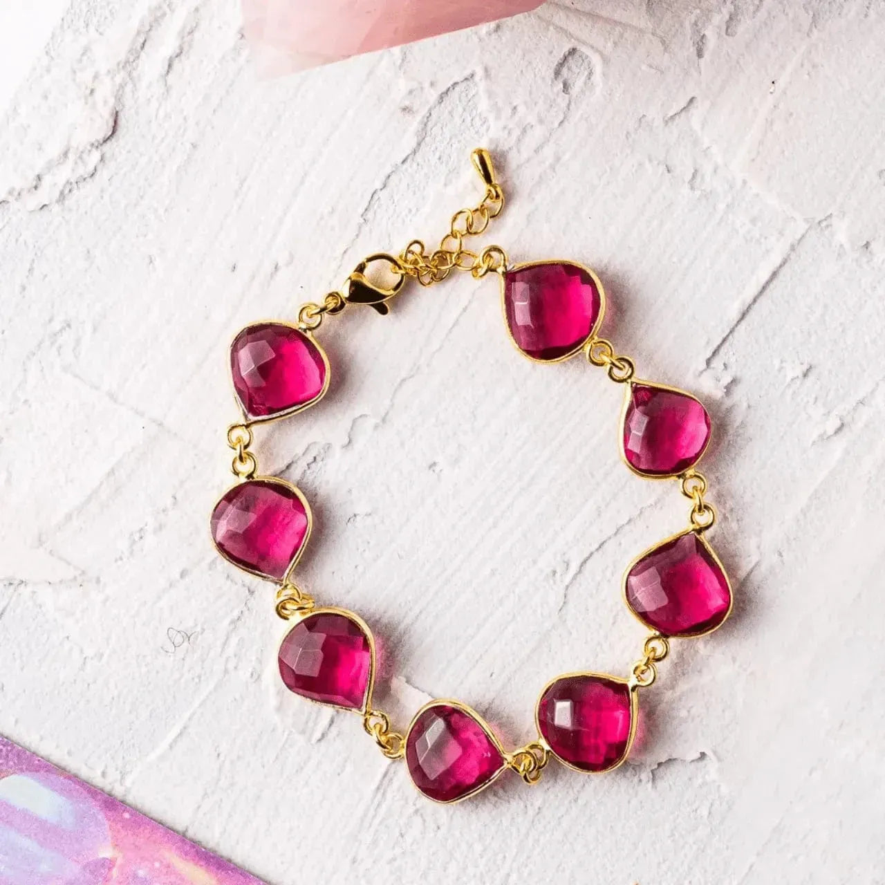 Bracelet with pink teardrop-shaped beads on a textured white surface