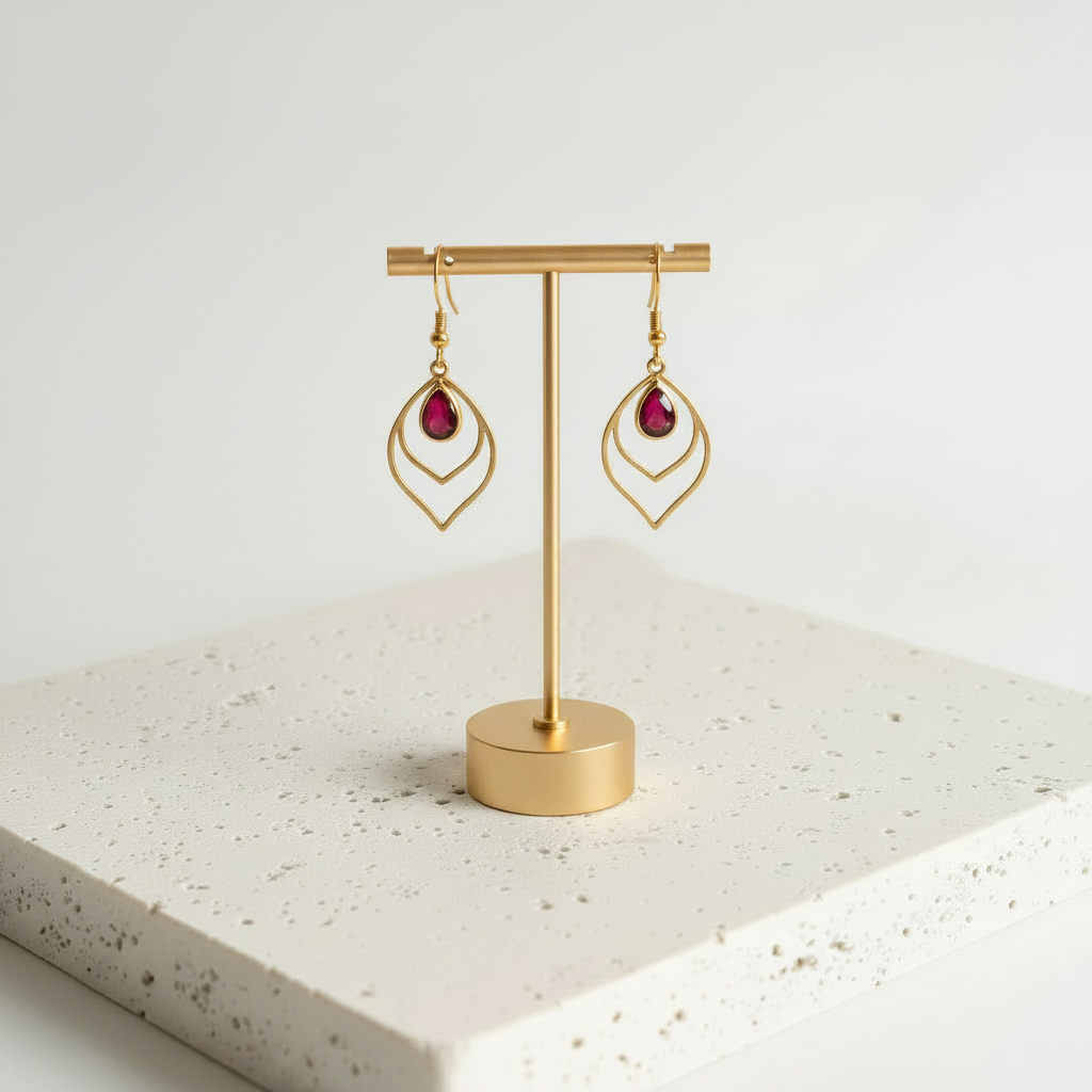 Red faceted glass teardrop earrings in gold, shown hanging
