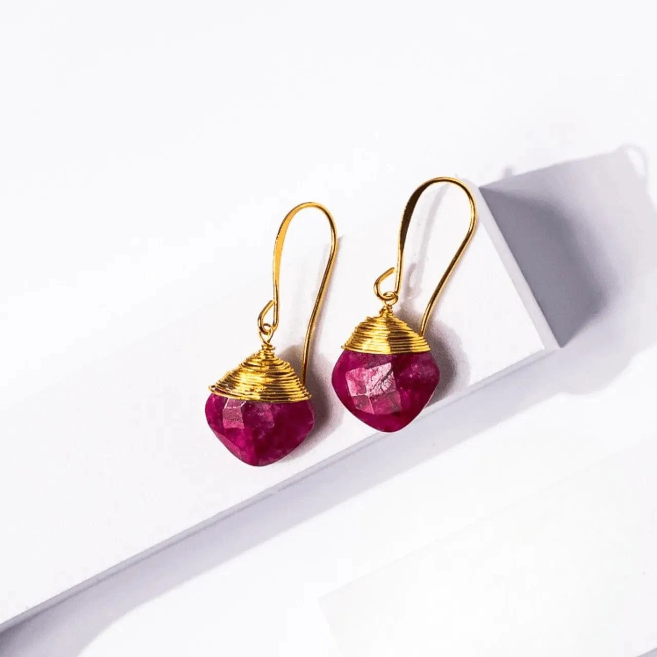 Gold earrings with pink gemstones on a white background