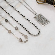 Necklace with gemstones and a decorative pendant on a marble surface
